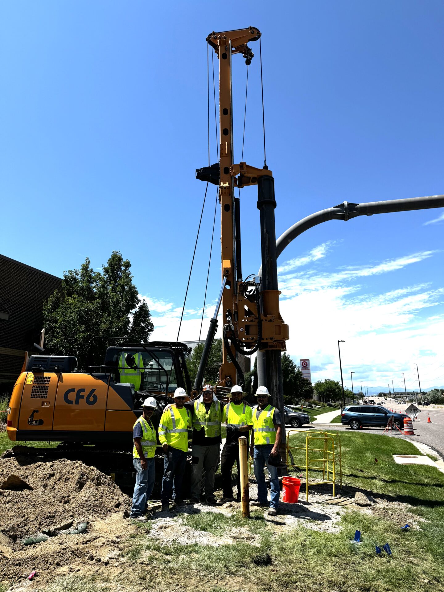 A group of people standing around a pile driver.